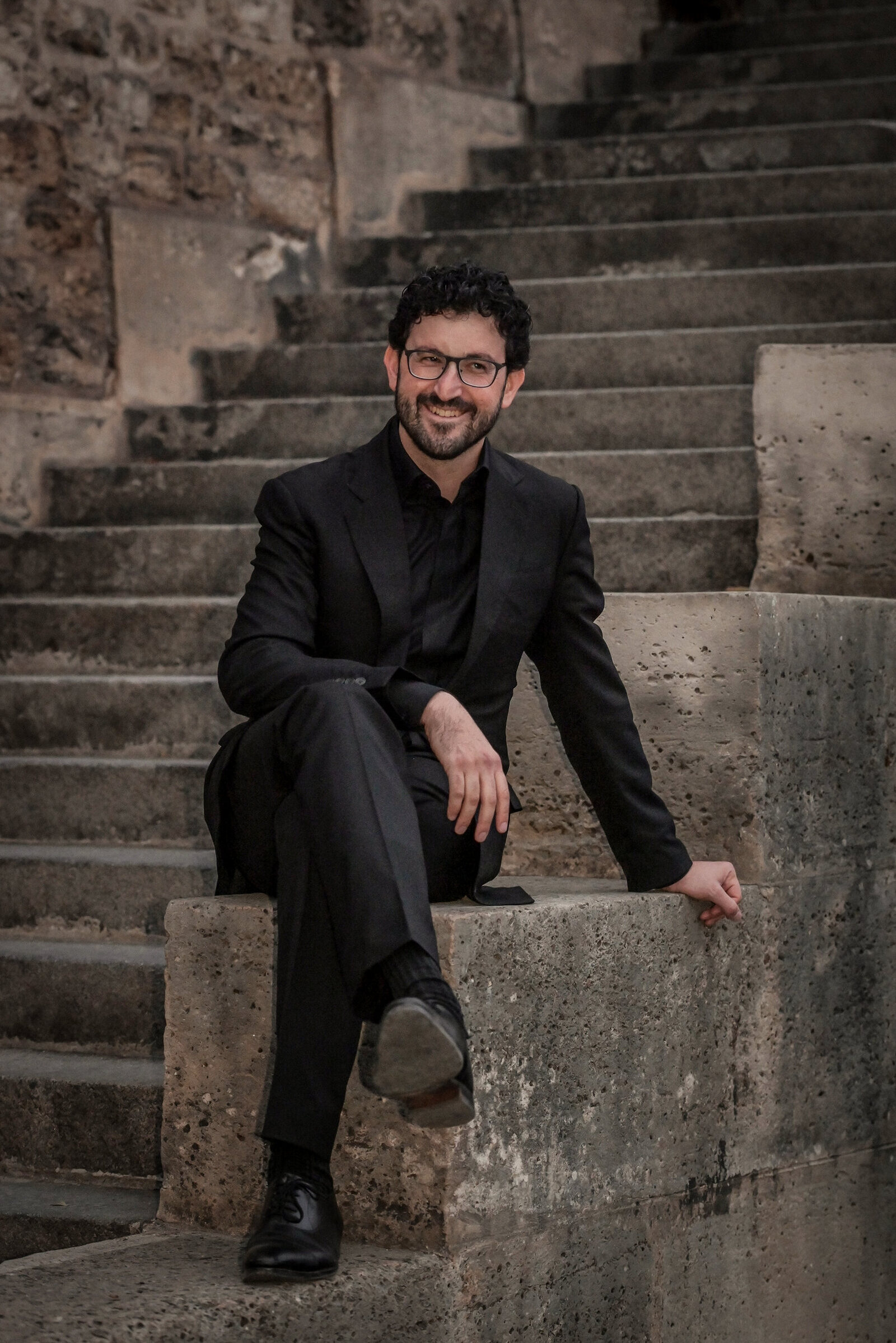 Ben Kazez seated on stone steps, smiling